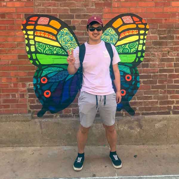 Vinnie standing in front of butterfly painting on wall in downtown Columbia, Missouri